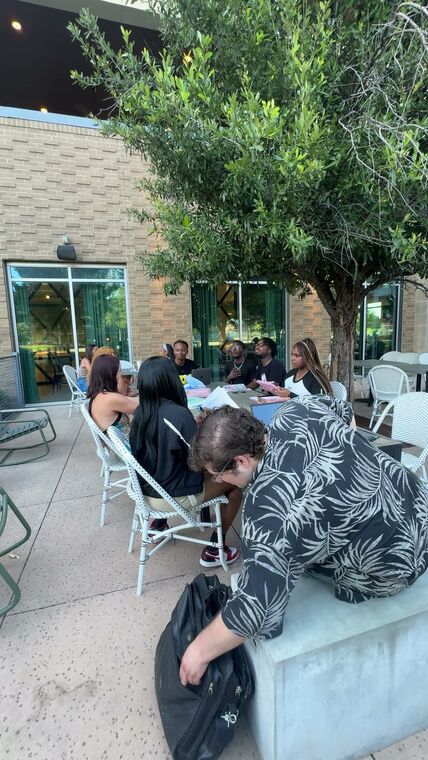 Members gathered at an outdoor table in a brick courtyard