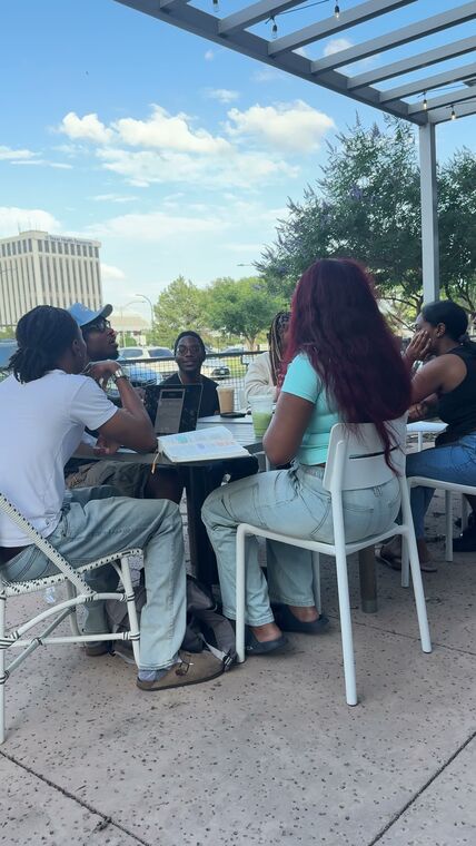A smaller group in discussion at a shaded patio table